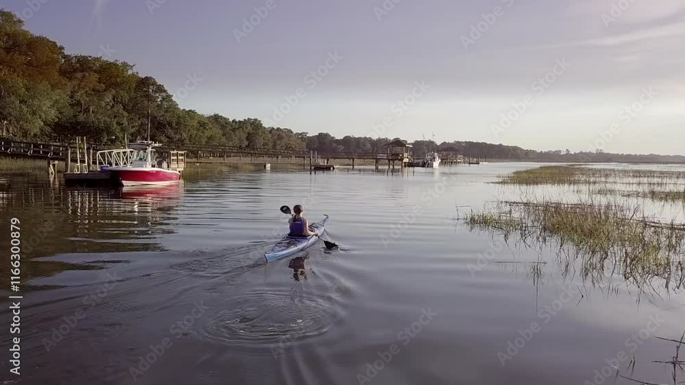 Low aerial shot of young woman kayaking on calm water at sunset. Low aerial shot of young woman kayaking on calm water at sunset.