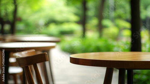 Serene outdoor space featuring wooden tables and chairs, surrounded by lush greenery, perfect for relaxation and casual dining. photo