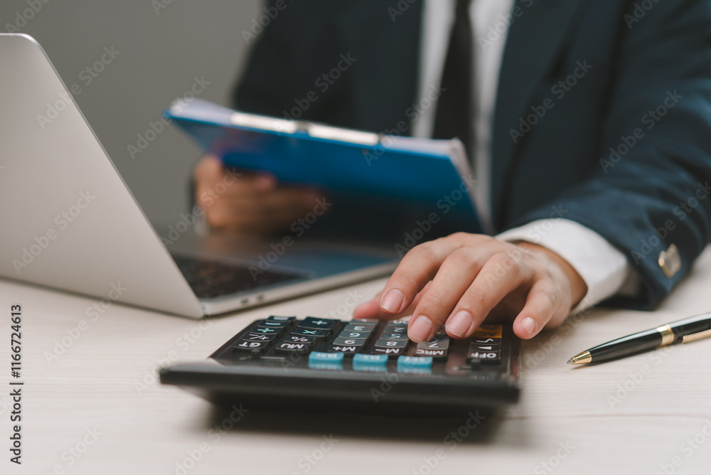 A businessman at his workplace uses a laptop and paper to manage payroll, tax, salary, and income, reflecting financial control and efficient office work. A businessman at his workplace uses a laptop and paper to manage payroll, tax, salary, and income, reflecting financial control and efficient office work.