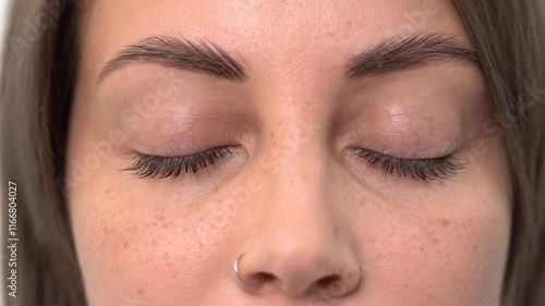 A beautiful young girl opens her eyes after eyelash lamination. Close-up, slow motion
