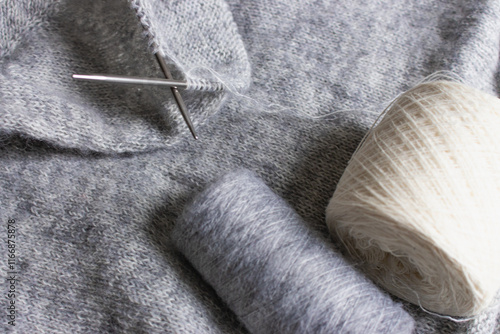 Obraz na płótnie Grey melange knitting sweater with knitting needles. Mix of grey wool and white cashmere with needles. Knitting pattern background. Knitting lifestyle. Cozy hobby. Warm knitwear. Craft product concept w salonie