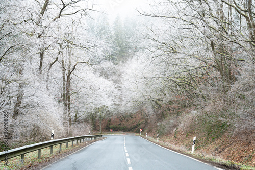 Icy snow covered road, ground frost in winter, moisture fog in morning, low visibility, slippery dangerous street, overcast weather photo