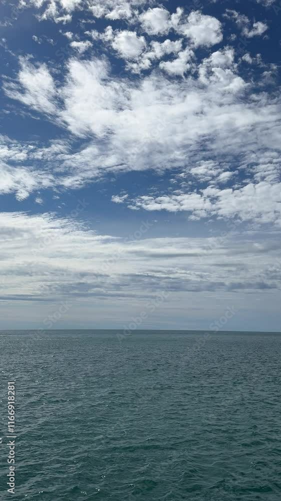 Blue ocean and clouds in sky, vertical video.