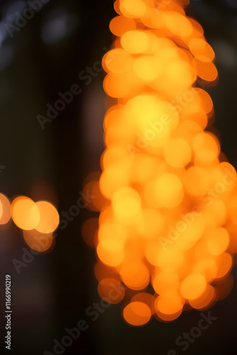 A blurred image featuring a series of warm orange bokeh lights, creating a dreamy and festive atmosphere. The lights are scattered and form abstract patterns against a soft background. photo