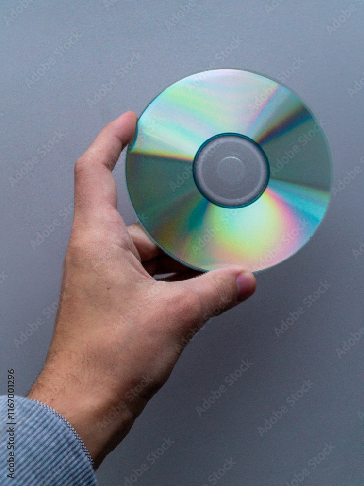 A series of three photographs showcasing a hand holding a CD or DVD against a plain background. Each image presents a slightly different angle or position of the hand and the disc, offering a variety A series of three photographs showcasing a hand holding a CD or DVD against a plain background. Each image presents a slightly different angle or position of the hand and the disc, offering a variety