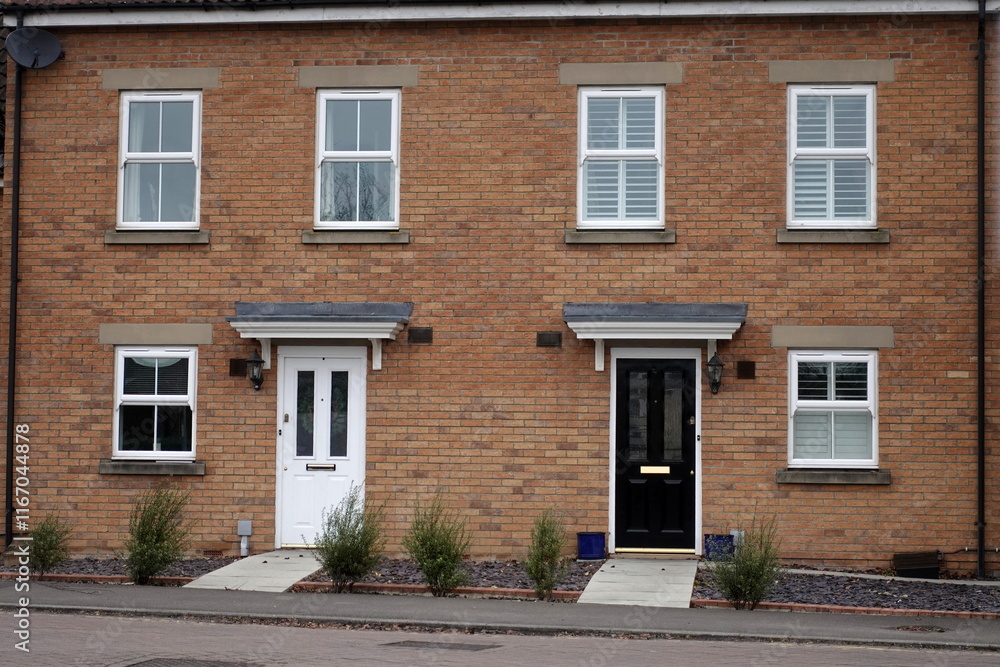 View of front doors and exteriors of two neighbouring red brick town houses on a street in an English city View of front doors and exteriors of two neighbouring red brick town houses on a street in an English city
