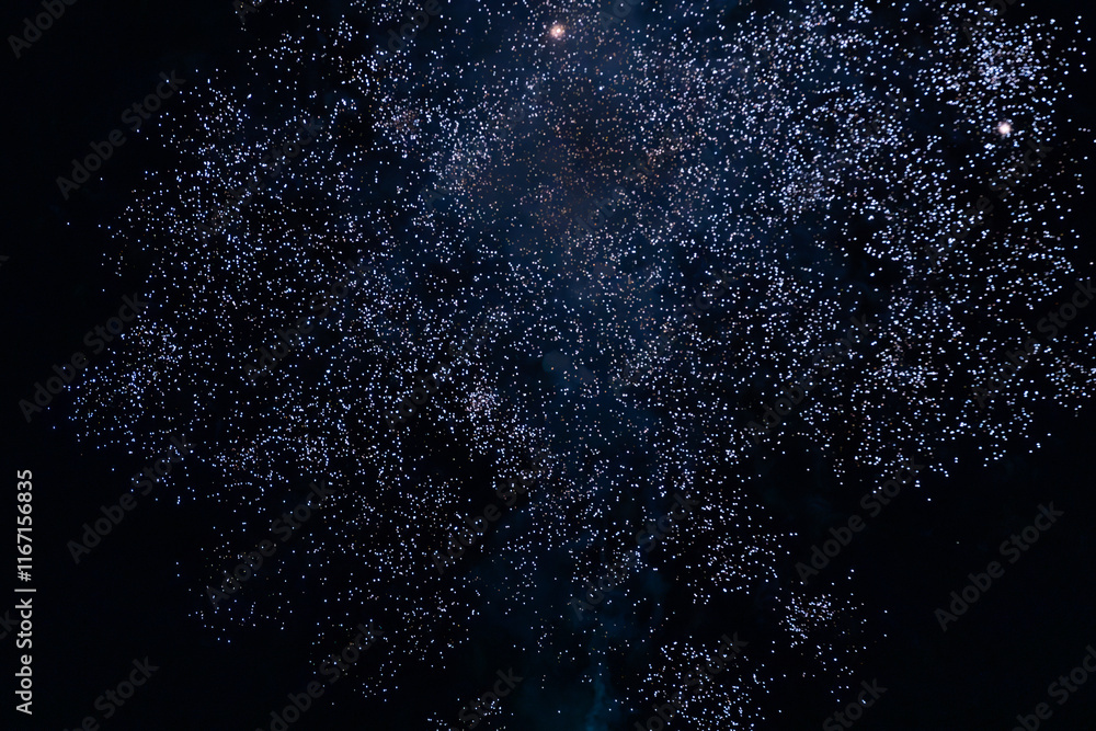 Obraz premium A dazzling display of golden fireworks streaking across the night sky, accented by vibrant red lights. The radiant patterns evoke a sense of celebration and excitement.