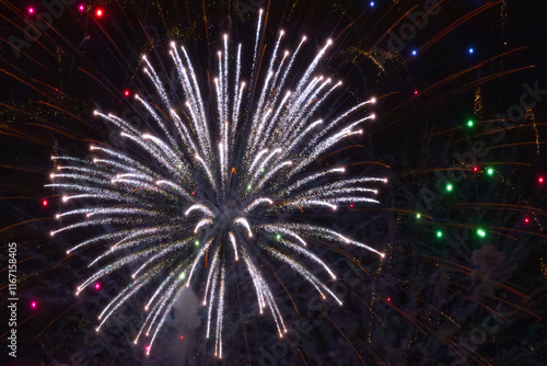 A dazzling display of golden fireworks bursts with star-like patterns, accompanied by soft blue specks of light against a dark sky. A magical and festive scene. photo