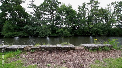 Video, View of  UK river Tone stone bank in foreground, trees behind.