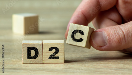 A hand arranging wooden blocks to form the acronym D2C, symbolizing direct-to-consumer business model and modern marketing strategies photo