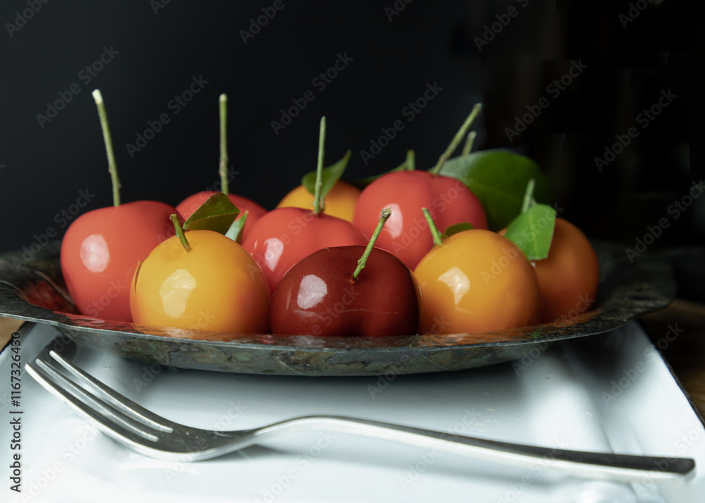 Deletable imitation fruits (Kanom look choup) has a sweet taste in small leaf shaped metal platter served with dessert fork. Traditional Thai sweet treats made from mung beans and coconut milk, jelly.