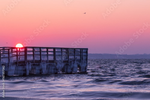 Obraz na płótnie Winter seascape with ice covered jetty at the Baltic Sea at sunrise. w salonie