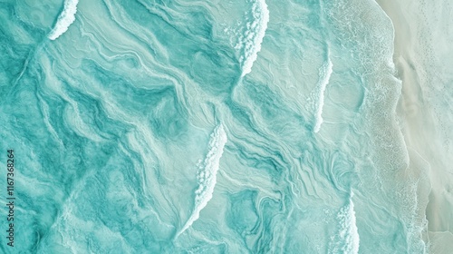 Aerial view of turquoise ocean waves meeting sandy beach.