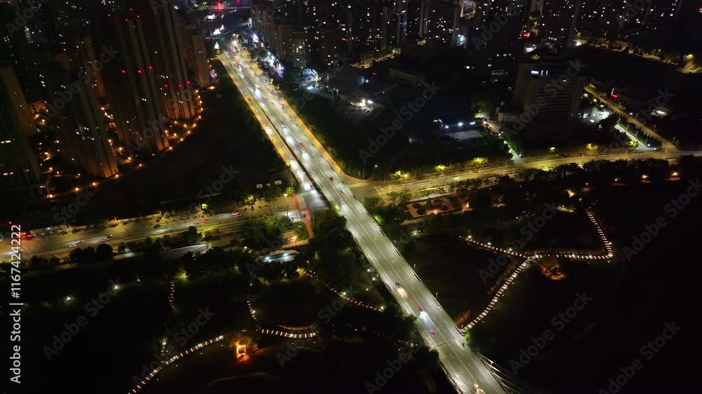 Nighttime aerial view of a bustling city intersection illuminated by streetlights and surrounding buildings Nighttime aerial view of a bustling city intersection illuminated by streetlights and surrounding buildings