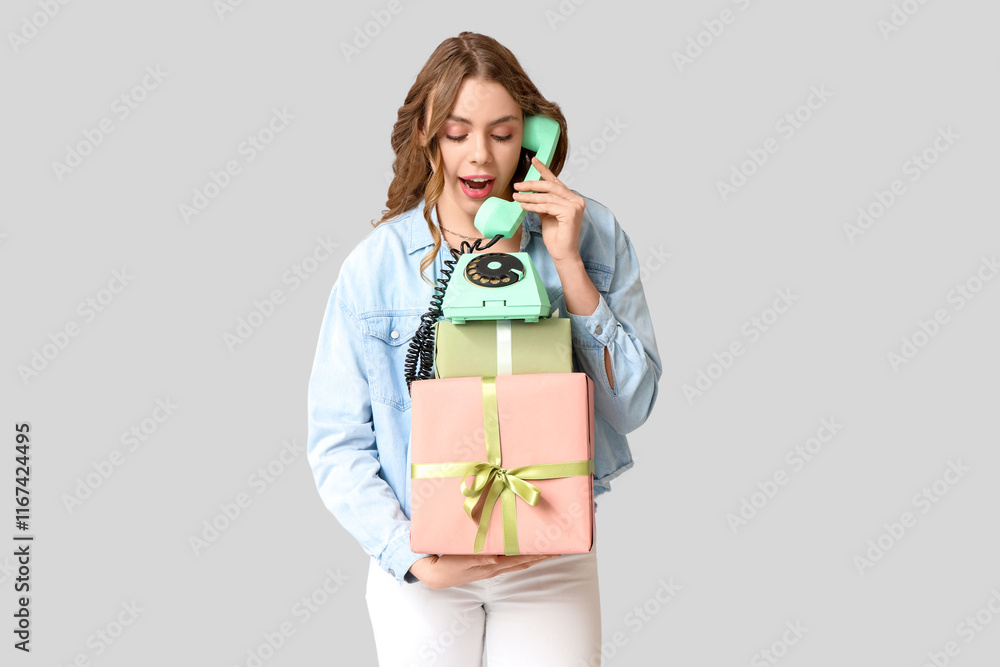 Young woman talking by retro telephone with gift boxes on grey background. International Women's Day Young woman talking by retro telephone with gift boxes on grey background. International Women's Day