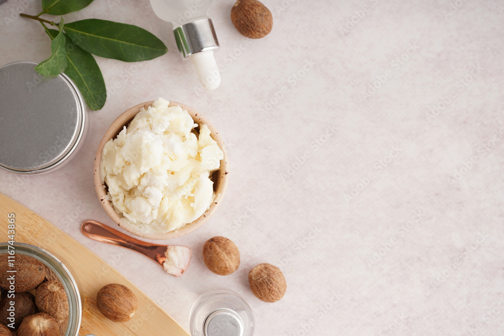 Fototapeta premium Composition with bowl of shea butter, nuts and cosmetic products on light background