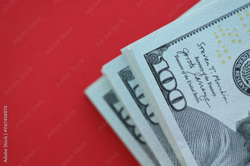 Big amount of hundred dollar bills in thick stack lies on bright red color paper background Big amount of hundred dollar bills in thick stack lies on bright red color paper background