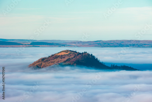 Rural valley filled with thick fog and large hills and farmland rising above photo