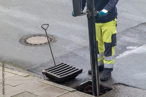 Arbeiter in Sicherheitskleidung reinigen einen Gully mit Absaugvorrichtung  photo