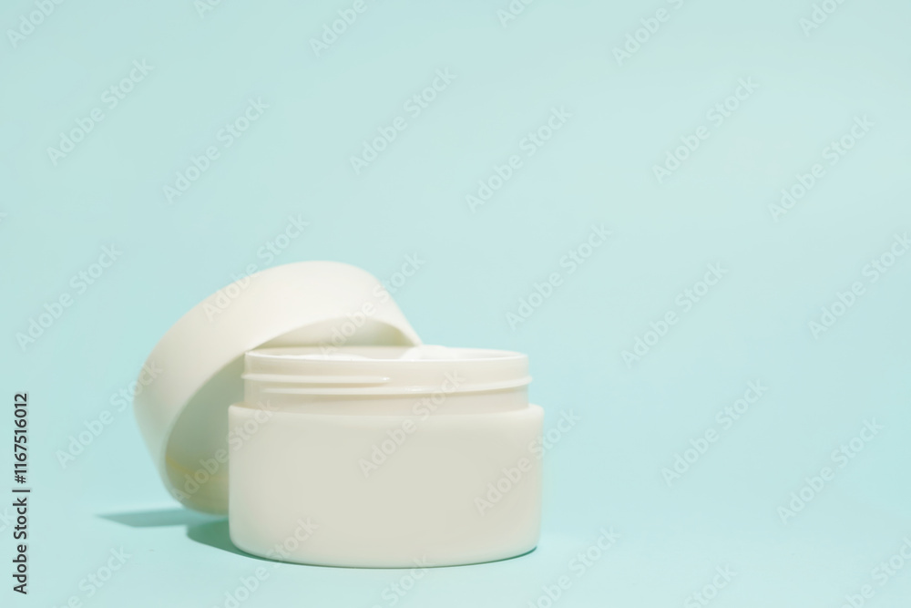 An open white cosmetic jar sits elegantly on a soft blue background An open white cosmetic jar sits elegantly on a soft blue background