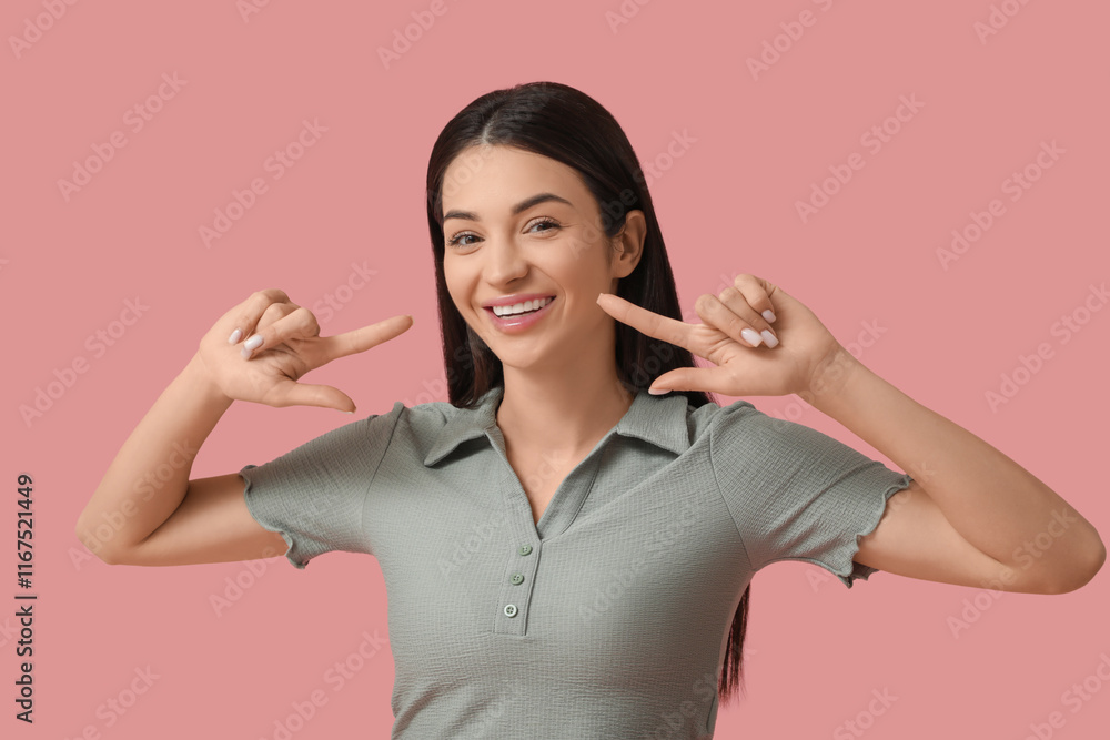 Beautiful young happy smiling woman pointing at her smile on pink background Beautiful young happy smiling woman pointing at her smile on pink background