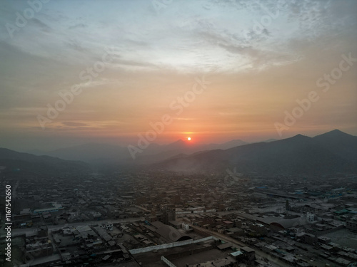 Foggy sunset over the city at the foot of the mountains