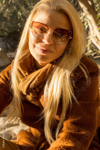 Blonde Woman Wearing Sunglasses and Scarf Relaxing Outdoors photo