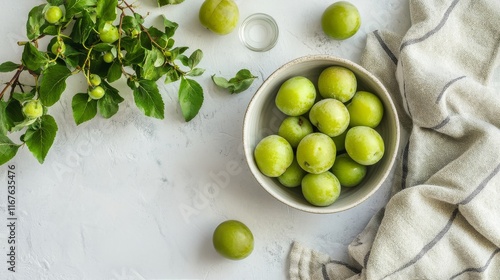 Fresh green plums in a wooden bowl with leaves on a textured surface
