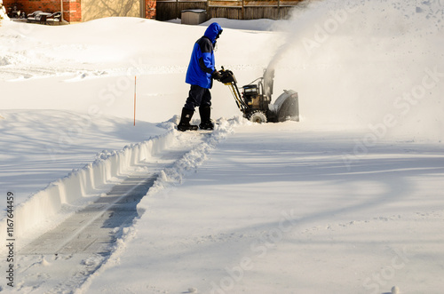 Side view of a man using a snow blower to begin clearing a residential driveway photo