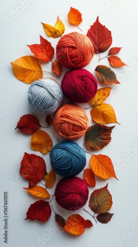 Colorful yarn balls surrounded by autumn leaves on a light background