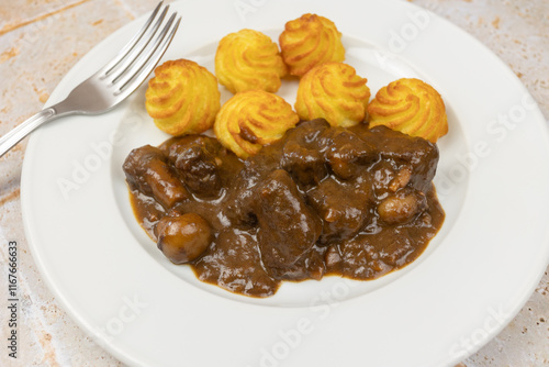 boeuf bourguignon et pommes de terre duchesse, en gros plan, dans une assiette photo