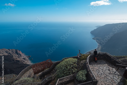 A beautiful view of the ocean with a man standing on a stone walkway watching the scenery photo