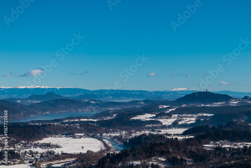 Scenic view of Pyramidenkogel and Lake Woerth in Rosental Valley seen from mount Petelin in Faak, Carinthia, Austria. Winter wonderland landscape. Austrian Alps covered in snow. Serenity and calmness photo