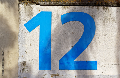 Number twelve in blue on white wall