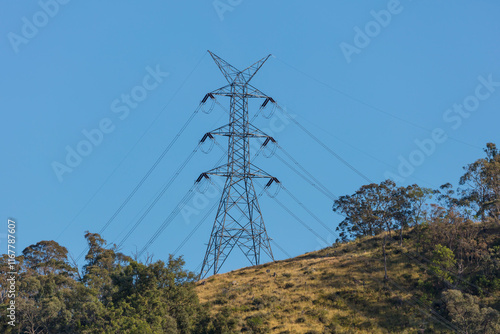 Photograph of a large steel electricity Transmission Tower on a grassy hill in regional Australia.