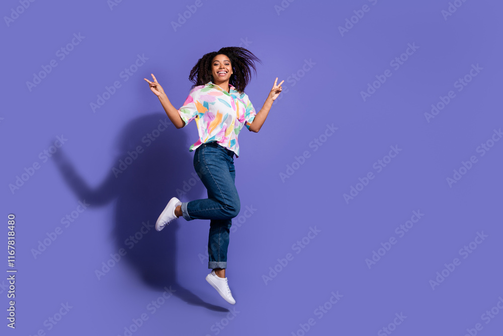 Joyful young woman jumps against a vibrant purple backdrop, showcasing cheerful energy.