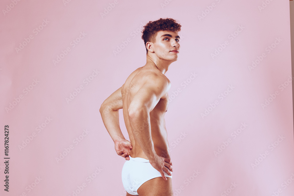 Confident young man posing in white underwear, standing against a pastel pink background, showcasing a fit physique. Body positivity and fashion concept. Confident young man posing in white underwear, standing against a pastel pink background, showcasing a fit physique. Body positivity and fashion concept.
