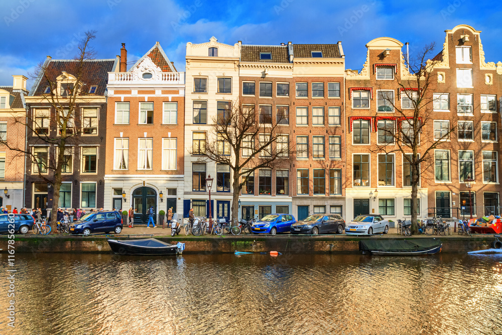 Cityscape on a sunny winter day - view of the houses and the city canal with boats in the historic center of Amsterdam, The Netherlands