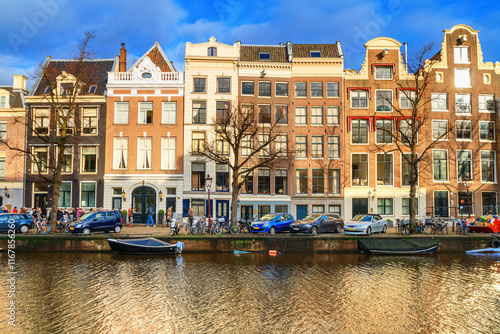 Obraz na płótnie Cityscape on a sunny winter day - view of the houses and the city canal with boats in the historic center of Amsterdam, The Netherlands w salonie