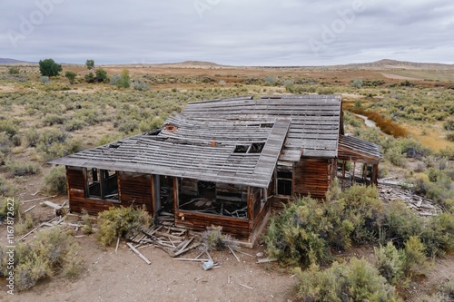 Abandoned wooden house in a desert landscape. Ruined structure surrounded by desert plants. A testament to time and nature's reclaiming. , Worland, Wyoming, USA. photo