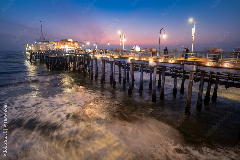 Santa Monica pier at dusk with people walking about and blurry ocean waves
Santa Monica pier at dusk with people walking about and blurry ocean waves