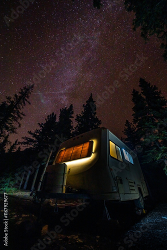 Camping under the stars, vintage travel trailer against beautiful milky way sky