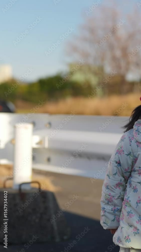 In December 2024, a 3-year-old Japanese girl spends a winter evening surrounded by guardrails in a parking lot in Fukuoka City, Fukuoka Prefecture. Vertical video. In December 2024, a 3-year-old Japanese girl spends a winter evening surrounded by guardrails in a parking lot in Fukuoka City, Fukuoka Prefecture. Vertical video.