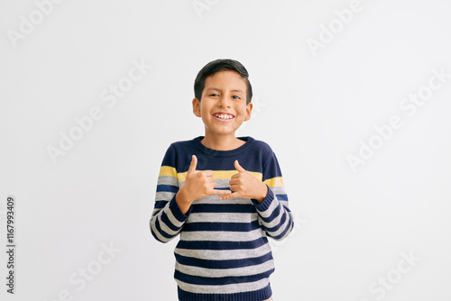 Boy wearing a striped sweater in blue, yellow, and gray tones, laughing genuinely and relaxed. White background highlights his joyful and natural expression photo