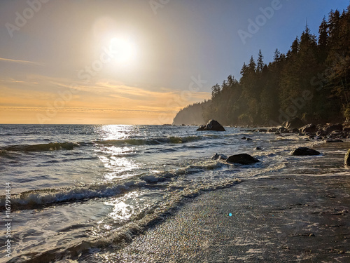 Fotografie Waves from the pacific ocean roll into a beach bathed in golden sunlight on Vanc