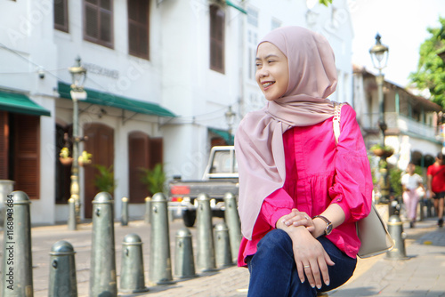 asian muslim woman sitting on the side of the street at Kota Lama or old town city, Semarang, Indonesia