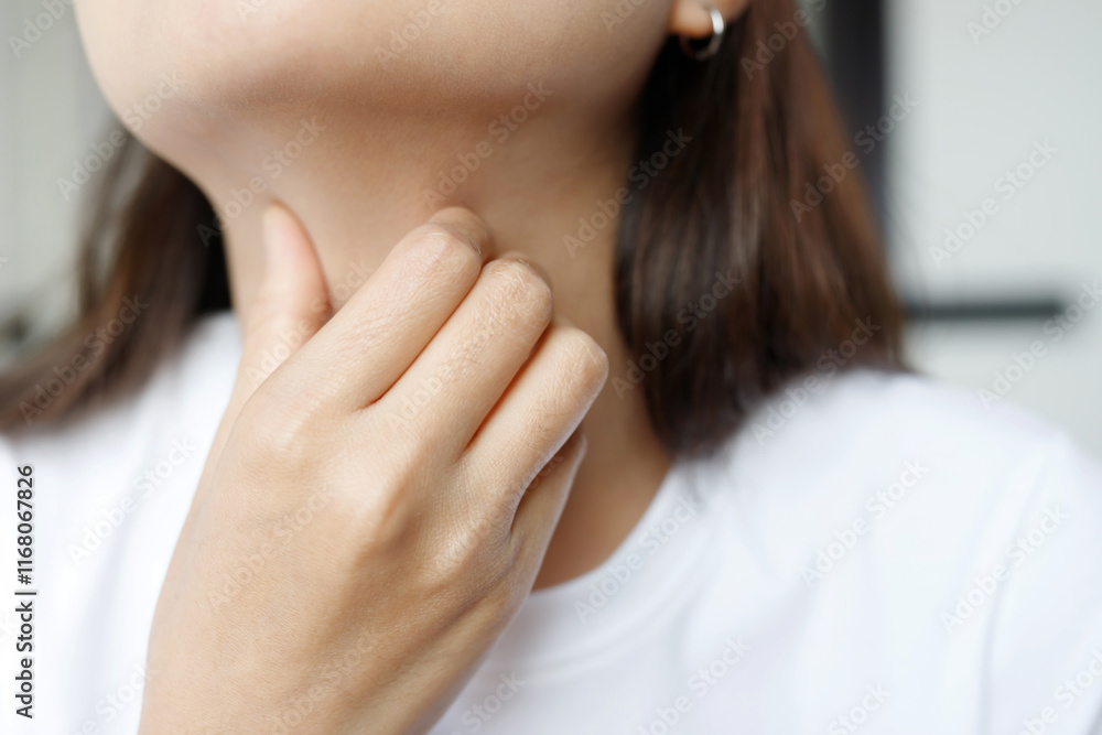 sore throat pain. Closeup of young woman sick holding her inflamed throat using hands to touch the ill neck in blue shirt on gray background. Medical and healthcare concept. sore throat pain. Closeup of young woman sick holding her inflamed throat using hands to touch the ill neck in blue shirt on gray background. Medical and healthcare concept.