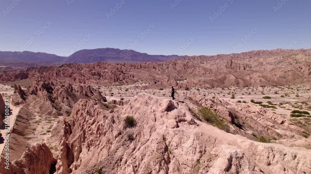 A man Exploring Stunning Rock Formations and Vast Landscapes in a Remote Desert Region During Bright Daylight A man Exploring Stunning Rock Formations and Vast Landscapes in a Remote Desert Region During Bright Daylight