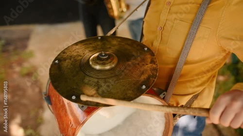 Close up drums on neck man. Hands holding drumsticks and beating outdoors. Portrait band members playing brass instruments on street during live concert. Ukrainian wedding traditions. Musician drummer