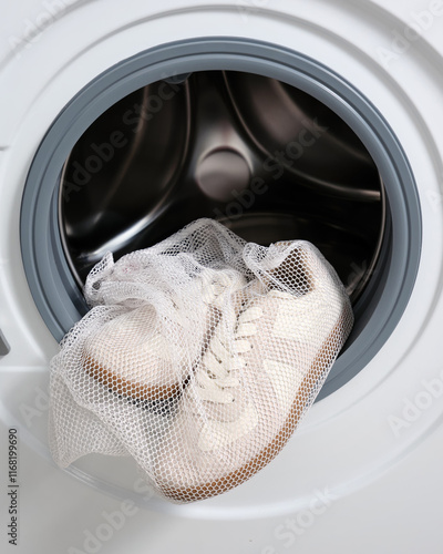 Vertical image of sports shoes in a laundry bag in a washing machine with the drum open. photo